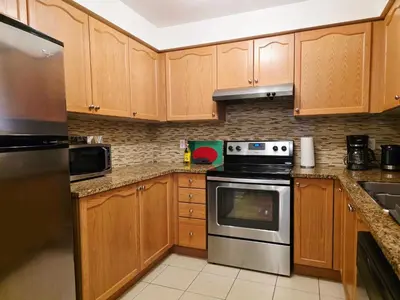 a kitchen with wooden cabinets and a stove top oven at Semi-Private Townhouse - 3 Bedrooms - 4 beds - Free Parking, Wifi, Netflix in Toronto