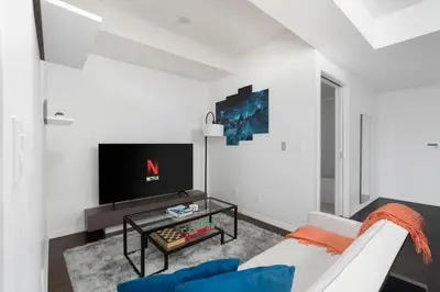 a living room with a couch and a tv at Stylish Condo with Private Patio in Fortyork in Toronto