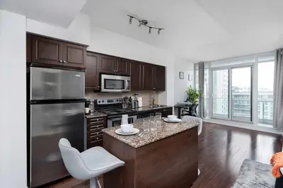a kitchen with a stainless steel refrigerator and a counter at Stylish Condo with Private Patio in Fortyork in Toronto