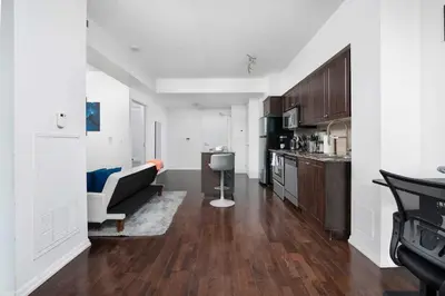 a living room with a couch and a kitchen at Stylish Condo with Private Patio in Fortyork in Toronto