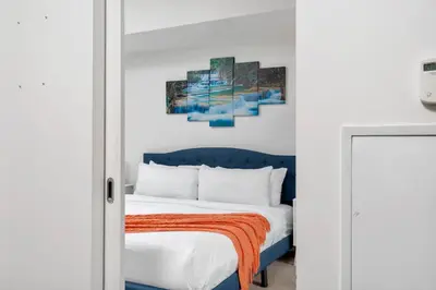 a bedroom with a blue bed and a painting on the wall at Stylish Condo with Private Patio in Fortyork in Toronto