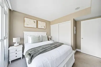 a bedroom with a white bed and a window at Spacious Toronto Condo w Patio - City Comfort in Toronto