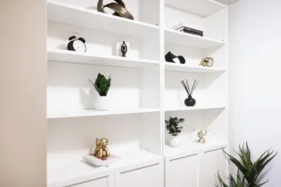a white book shelf with various items on it at Spacious Toronto Condo w Patio - City Comfort in Toronto