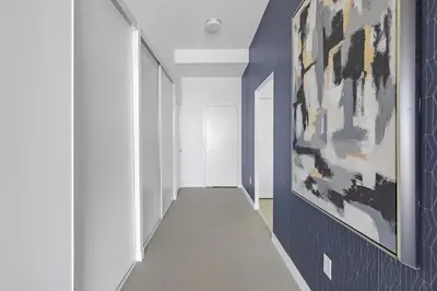 a hallway with blue walls and a painting on the wall at Sky-High Penthouse Breathtaking City Views in Toronto