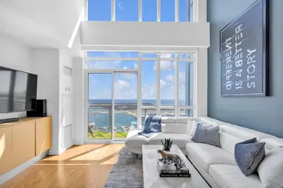 a living room with a white couch and a large window at Sky-High Penthouse Breathtaking City Views in Toronto