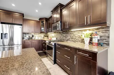 a kitchen with wooden cabinets and stainless steel appliances at Pool, King Bed, Patio with BBQ, Fall Hiking Nearby in Cambridge