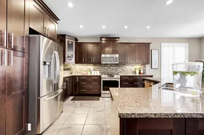 a kitchen with wooden cabinets and a stainless steel refrigerator at Pool, King Bed, Patio with BBQ, Fall Hiking Nearby in Cambridge