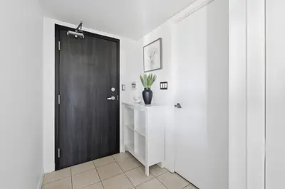 a hallway with a black door and white walls at Stylish 2BR Downtown Escape Prime Victoria Spot in Toronto