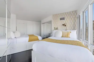 a white bedroom with two beds and a window at Stylish 2BR Downtown Escape Prime Victoria Spot in Toronto