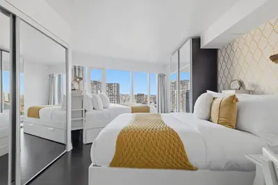 a white bedroom with two beds and a large window at Stylish 2BR Downtown Escape Prime Victoria Spot in Toronto