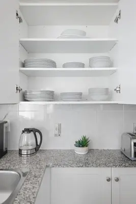 a kitchen with white cabinets and white plates on shelves at Stylish 2BR Downtown Escape Prime Victoria Spot in Toronto
