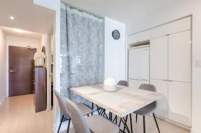 a white dining room with a table and chairs at Modern 2 Bedroom plus Den Condo with Balcony Downtown Toronto in Toronto