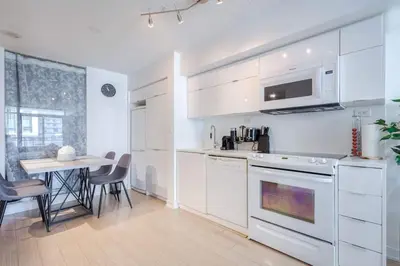 a kitchen with white appliances and a table with chairs at Modern 2 Bedroom plus Den Condo with Balcony Downtown Toronto in Toronto