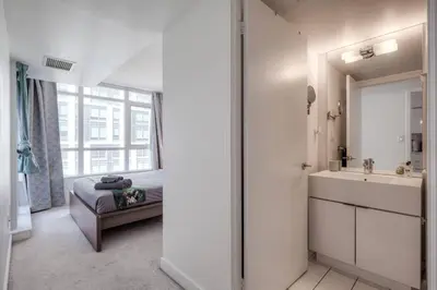 a white bathroom with a sink and a mirror at Modern 2 Bedroom plus Den Condo with Balcony Downtown Toronto in Toronto