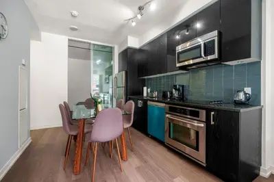 a kitchen with a table and chairs and a microwave at New Modern 2 Bedroom 2 Bath Apartment with Balcony in Toronto