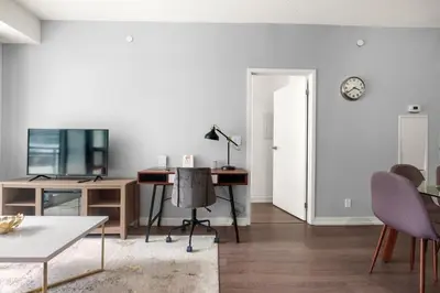 a living room with a desk and a clock on the wall at New Modern 2 Bedroom 2 Bath Apartment with Balcony in Toronto