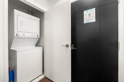 a laundry room with a washer and a black door at New Modern 2 Bedroom 2 Bath Apartment with Balcony in Toronto
