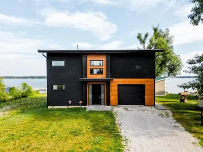a black house with an orange door on a grass field at Casa Luna Chic Lakehouse BBQ Game Room LakeViews in Orillia