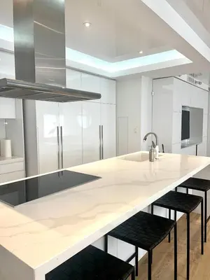 a kitchen with white cabinets and a large island with stools at Camden Haus Loft in Toronto