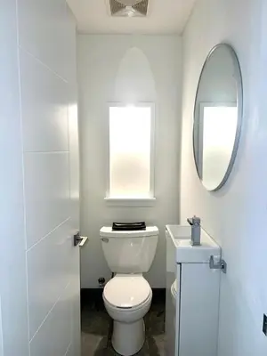 a bathroom with a white toilet and a mirror at Camden Haus Loft in Toronto