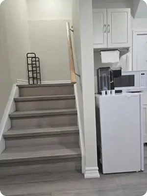 a kitchen with stairs with a microwave and a refrigerator at Charming Suite in Cambridge