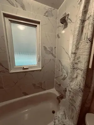a bathroom with a window and a tub with a shower curtain at Relax in East York Space Share in Toronto