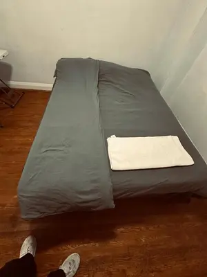 a gray bed sitting on a wooden floor in a room at Relax in East York Space Share in Toronto