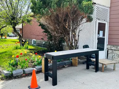 a black bench sitting on a sidewalk next to a garden at Relax in East York Space Share in Toronto
