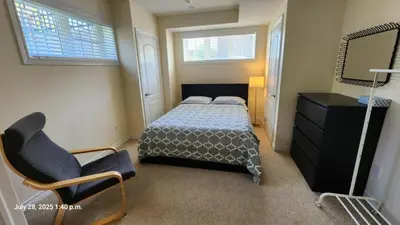 a bedroom with a bed and a chair and a mirror at Spacious 2 BR, 3 beds, sleeps 6, kitchen, laundry in Richmond Hill