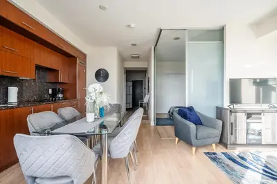 a kitchen and living room with a glass table and chairs at Cozy 1 BR & Den Condo in North York Free Parking in Toronto