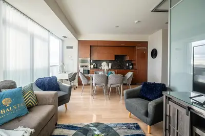 a living room with a couch and chairs and a kitchen at Cozy 1 BR & Den Condo in North York Free Parking in Toronto