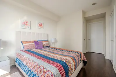 a white bedroom with a bed with a colorful comforter at Modern 2Bd 2Ba Skyscraper Free parking in Toronto