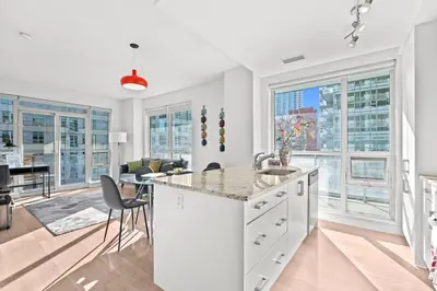 an open kitchen and living room with large windows at Modern New 2Bd 2Ba &Den Condo with Balcony in Toronto