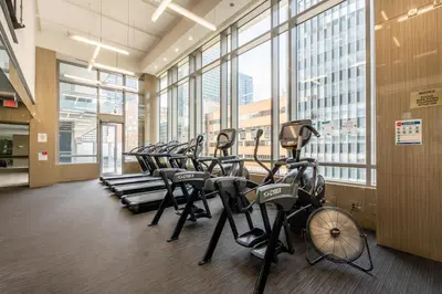 a row of exercise bikes in a gym with windows at Modern New 2Bd 2Ba &Den Condo with Balcony in Toronto
