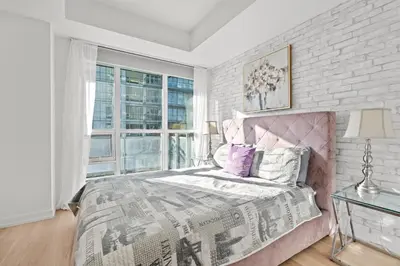 a bedroom with a pink bed and a brick wall at Modern New 2Bd 2Ba &Den Condo with Balcony in Toronto