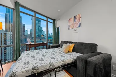 a bedroom with a couch and a large window at 1BR High Floor View Downtown Toronto in Toronto