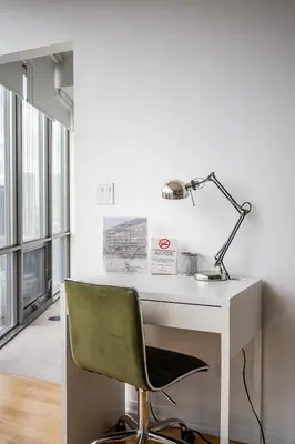 a white desk with a green chair and a lamp at 1BR High Floor View Downtown Toronto in Toronto