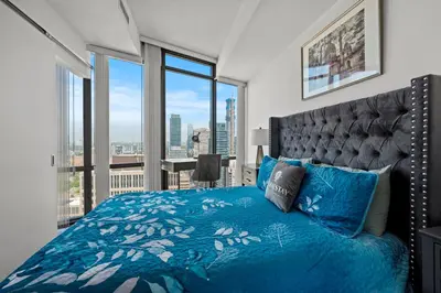 a bedroom with a blue bed with a large window at Magnificent 1 Bd High floor view Downtown Toronto in Toronto