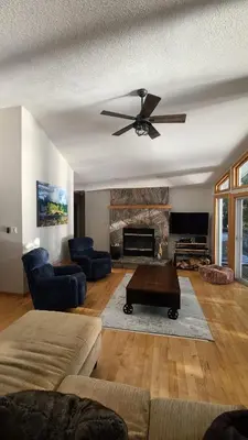 a living room with a ceiling fan and a fireplace at Sunset Heaven 3 Bedroom Lakefront Retreat in Bracebridge