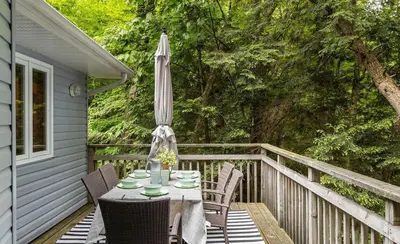 a table and chairs on a porch with an umbrella at Sunset Heaven 3 Bedroom Lakefront Retreat in Bracebridge