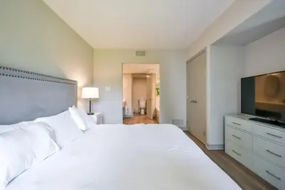 a bedroom with a large white bed and a flat screen tv at Perfect Jacuzzi Suite at Highland in Shanty Bay