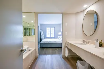 a bathroom with a sink and a mirror and a bed at Perfect Jacuzzi Suite at Highland in Shanty Bay