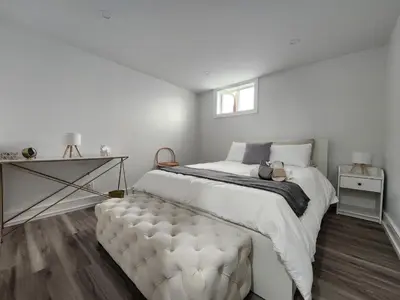 a white bedroom with a large bed and a window at Entire 2BR Apt in Midtown Toronto, walk to Subway & Shops in Toronto