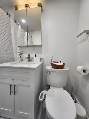 a white bathroom with a toilet and a sink at Entire 2BR Apt in Midtown Toronto, walk to Subway & Shops in Toronto