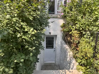 a white door on a white house with plants at Entire 2BR Apt in Midtown Toronto, walk to Subway & Shops in Toronto
