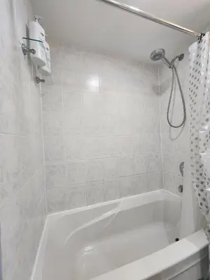 a white bathroom with a tub and a shower at Entire 2BR Apt in Midtown Toronto, walk to Subway & Shops in Toronto