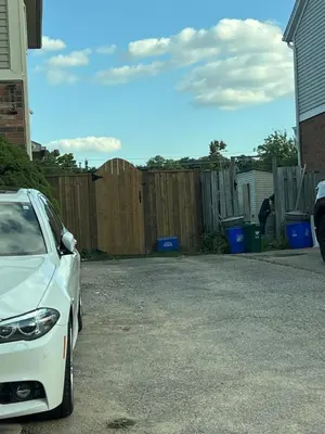 a white car parked in a driveway next to a fence at Studio Basement Apartment in Kitchener