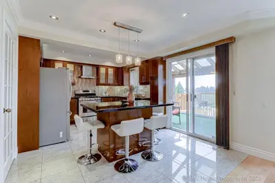 a kitchen with a bar with white stools at Prestige Manor, 6BR with Sunroom and 3400 Sqft by Instant Suites in Mississauga