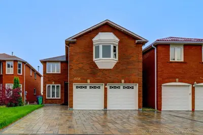 a brick house with two white garage doors at Prestige Manor, 6BR with Sunroom and 3400 Sqft by Instant Suites in Mississauga