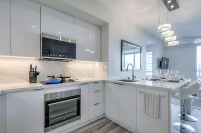 a white kitchen with white cabinets and a sink at Down Town CN Tower View 2BR Condo with Balcony and WiFi in Toronto